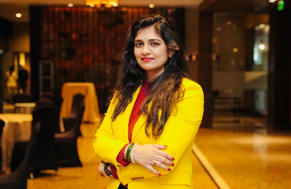 Ritu Singh, holistic life coach, smiling in a yellow blazer